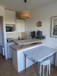 une cuisine avec une table et un comptoir dans l'établissement Joli studio avec piscine à 200m de la plage parking privé, à La Grande Motte
