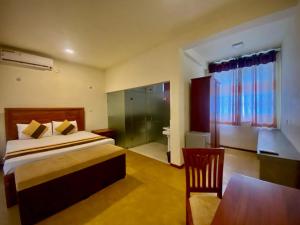 a bedroom with a bed and a table and a chair at Woodnest Villa Rustic in Kochchikade