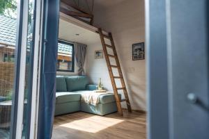 a couch in a tiny house with a ladder at Klimatyzowane Domki PREMIUM - Maszoperia Sun4Hel - Letnia Baza SnowShow na Półwyspie Helskim in Jastarnia