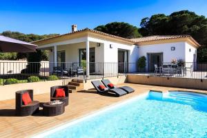 a swimming pool with chairs and a house at Villa La Pinède - Calvi in Calvi