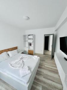 a white bedroom with a bed and a flat screen tv at Sea Panorama Apartments & Free Parking in Năvodari