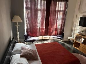 a bedroom with a bed and a window with red curtains at Chambre Neptune in Brussels