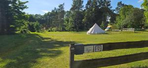 a white tent in a field with a fence at Mietwohnwagen inklusive Stellplatz & Strom - Dixi-WC in Carpin