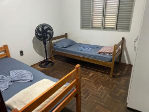 een kamer met 2 bedden en een ventilator bij Pousada da Dindinha Cacia in Monte Alegre de Minas +5 foto's