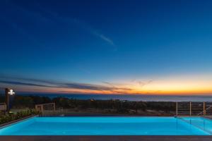a swimming pool with a view of the ocean at sunset at Diamond Star Hotel in Falasarna