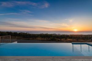 a pool with a view of the ocean at sunset at Diamond Star Hotel in Falasarna