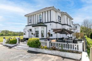 布里克瑟姆The Station Guest House的有篱笆和遮阳伞的白色房子