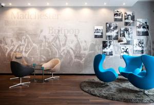 a lobby with blue chairs and a wall with pictures at Motel One Manchester-Piccadilly in Manchester