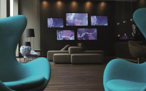 a living room with blue chairs and televisions at Motel One Manchester-Piccadilly in Manchester