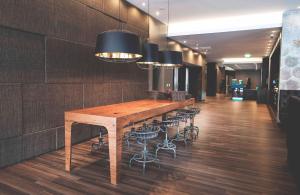 a long wooden table in a room with stools at Motel One Manchester-Piccadilly in Manchester