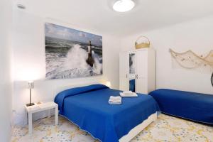 a bedroom with a blue bed and a picture of a lighthouse at Blueandgreen Apartment Amalfi Coast in Maiori