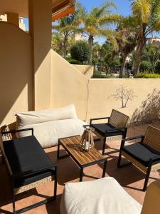 a patio with chairs and tables and palm trees at Espectacular casa Playas de Vera in Playas de Vera
