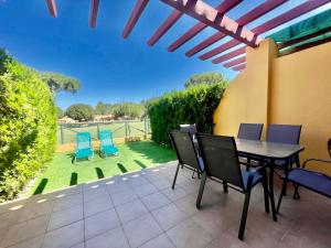 eine Terrasse mit einem Tisch, Stühlen und einer Liegewiese in der Unterkunft ALBATROS GOLF - ISLANTILLA in Islantilla