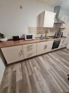 a kitchen with white cabinets and a wooden floor at Moderne, ruhige Ferienwohnung! in Geistingen