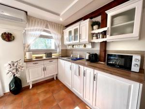 a kitchen with white cabinets and a microwave at Tia Maria in Győr