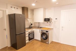 a kitchen with a refrigerator and a washing machine at Apartamentos Hotel Carlos I in Yuncos