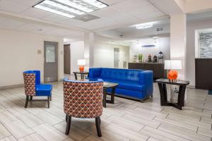 a lobby with a blue couch and tables and chairs at Quality Inn Jacksonville near Camp Lejeune in Jacksonville
