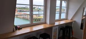 une pièce avec trois fenêtres avec vue sur une rivière dans l'établissement L'escale marine, à Calais
