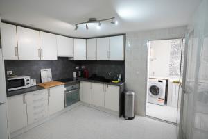 a kitchen with white cabinets and a washer and dryer at El rincón Del Prado apartamento con 4 AC in Gandía