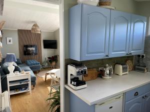 a kitchen with blue cabinets and a living room at Cosy private Chalet in Tywyn
