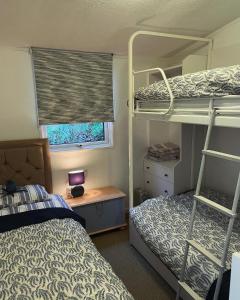 een slaapkamer met 2 stapelbedden, een bureau en een raam bij Cosy private Chalet in Tywyn +12 foto's