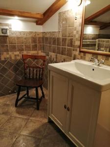 a bathroom with a sink and a mirror and a chair at Apartma na podeželju - Slovenia Nature in Kanal +25 photos