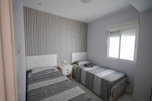 a bedroom with two beds and a window at El rincón Del Prado apartamento con 4 AC in Gandía