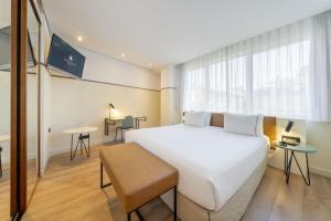a bedroom with a large white bed and a table at Eurostars Acteón in Valencia