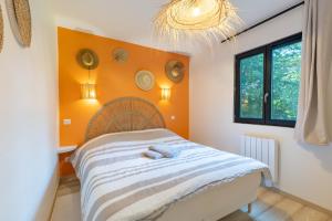 a bedroom with a bed with an orange wall at La Cabane Ô Rêves in Genouilleux