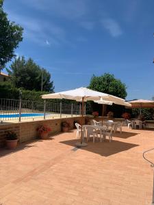a patio with tables and umbrellas next to a pool at Agriturismo cerquatonda in Montalto delle Marche