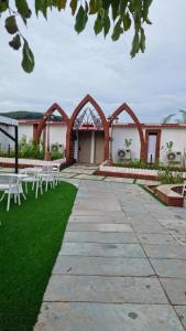 a building with white tables and chairs on the grass at Nostravila in Lonavala