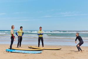 a group of men standing on surfboards on the beach at TAIGA Conil in Conil de la Frontera
