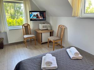 a bedroom with a bed and two chairs and a tv at DW Róża Wiatrów in Dębki +76 photos