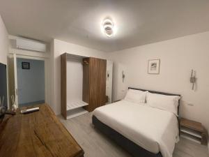 - une chambre avec un lit blanc et une table en bois dans l'établissement Saint Michel 3 piano, à Gorizia