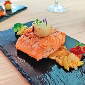 a plate of food with salmon and vegetables on a table at Resort El Paraíso Secreto in Miller