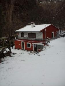 a red house with a snow covered roof in the snow at El cortijo azul in Güéjar-Sierra
