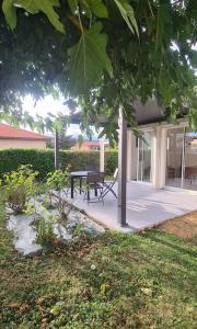 a patio with a table and a bench under a tree at Maison d'architecte in Cébazat