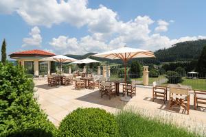 a patio with tables and chairs and umbrellas at Ailwaldhof Parkhotel & Spa in Baiersbronn