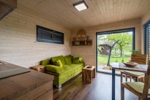a living room with a green couch and a table at Luxusní chaty v Ráji & Romantický posed s výhledem na Trosky in Újezd pod Troskami