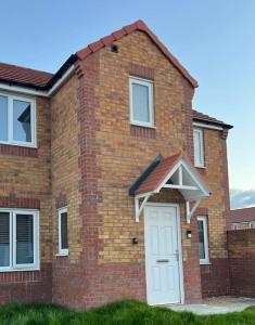 a brick house with a white door at Beautiful 3 Bed Detached House in Grimsby in Little Coates
