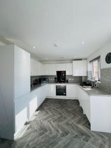 a kitchen with white cabinets and a wooden floor at Beautiful 3 Bed Detached House in Grimsby in Little Coates
