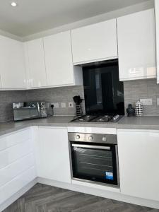 a kitchen with white cabinets and an oven at Beautiful 3 Bed Detached House in Grimsby in Little Coates
