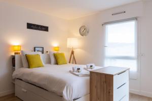 Un dormitorio con una gran cama blanca con almohadas amarillas. en GuestReady - Studio Gerland neuf avec terrasse, en La Mulatière