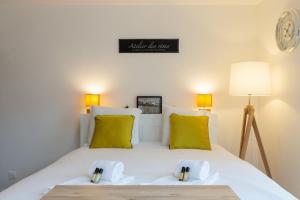 Un dormitorio con una cama con almohadas amarillas y un reloj. en GuestReady - Studio Gerland neuf avec terrasse, en La Mulatière 3 fotos más