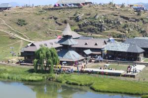 a large building on a hill next to a river at Parashar lake Fogg hill Resort in Prashar lake