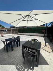 two tables and chairs under an umbrella on a patio at Carmen’s house in Nettuno