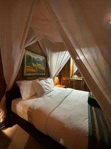 バニュウェダンにあるLeBulu Menjanganのベッドルーム(天蓋付き白いベッド1台付)