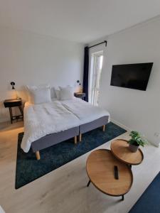 a white bedroom with a bed and two tables at Harbour Inn Hundested in Hundested