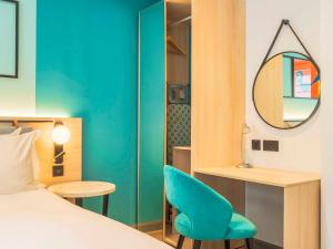 a room with a bed and a chair and a mirror at Holyrood Aparthotel in Edinburgh