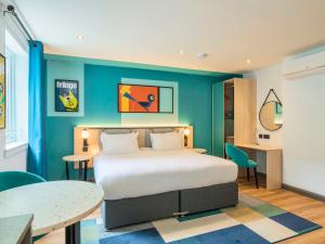 a bedroom with a bed and a blue wall at Holyrood Aparthotel in Edinburgh